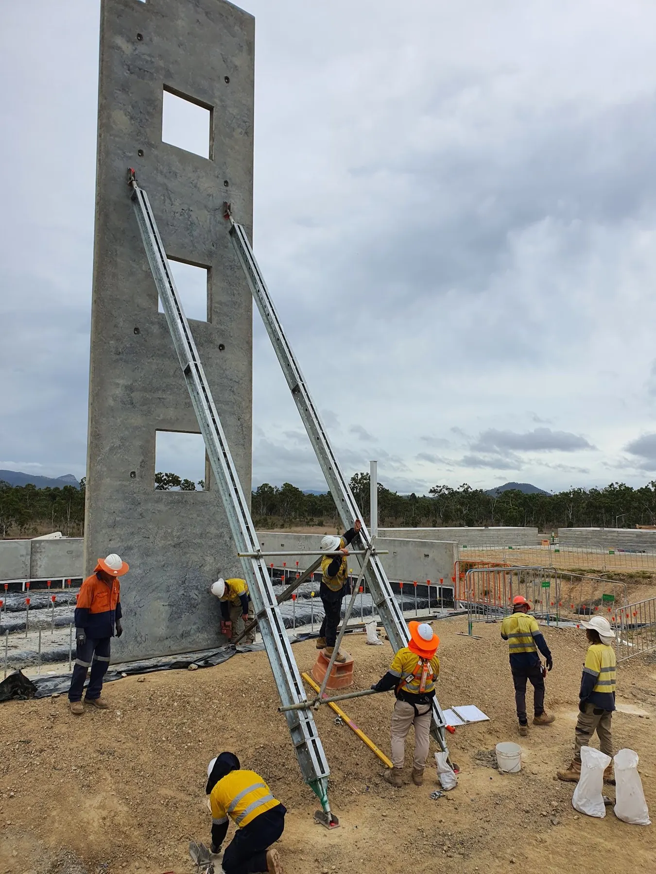 A crew bracing a tilt-up concrete panel on a construction site